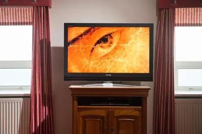 a flat screen tv sitting on a wooden stand with two windows at Regency Hotel in Douglas