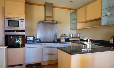 a kitchen with stainless steel appliances and wooden cabinets at Underscar - Great Gable in Keswick