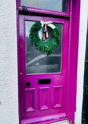 a pink door with a wreath and a bell on it at Vulcan Apartment - 3 Bedrooms - Sleeps 6 in Workington