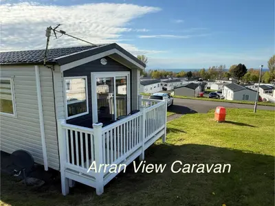 a tiny house with a porch in a yard at Arran View Caravan in Ayr