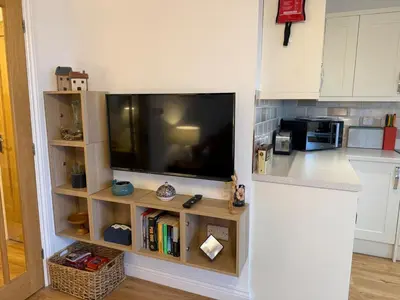a kitchen with a flat screen tv on a wall at Cliff Cottage Beautifully appointed apartment with world class view in Peel