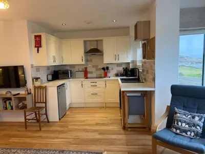 a kitchen with white cabinets and a blue chair at Cliff Cottage Beautifully appointed apartment with world class view in Peel