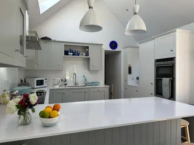 a kitchen with white cabinets and a bowl of fruit on a counter at Charming Cotswold stone cottage with garden in Moffat