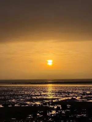 a sunset over the ocean with the sun in the sky at Paws A While in Mainsriddle