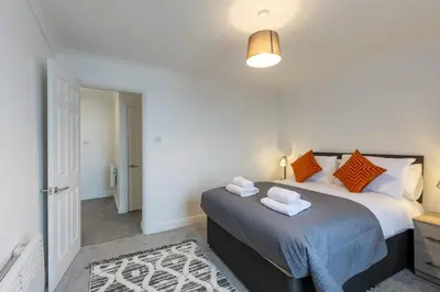 a bedroom with a bed with orange and blue pillows at 1 Bed Whitehaven Harbour-side Flat with Sea Views in Whitehaven