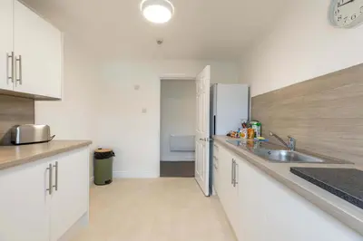 a kitchen with white cabinets and a stainless steel refrigerator at Bright 1 Bed Harbour-side Apartment w Sea Views in Whitehaven