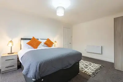 a bedroom with a large bed with orange pillows at Bright 1 Bed Harbour-side Apartment w Sea Views in Whitehaven