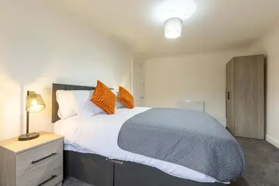 a bedroom with a large bed with orange pillows at Bright 1 Bed Harbour-side Apartment w Sea Views in Whitehaven