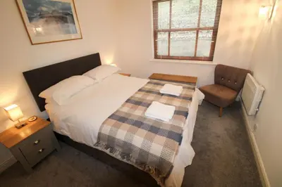 a small bedroom with a bed and a chair at Cedarfells, Hewetson Court, central Keswick with parking in Keswick