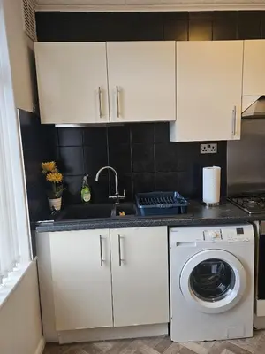 a kitchen with white cabinets and a washing machine at Acadia House Blyth in Moffat