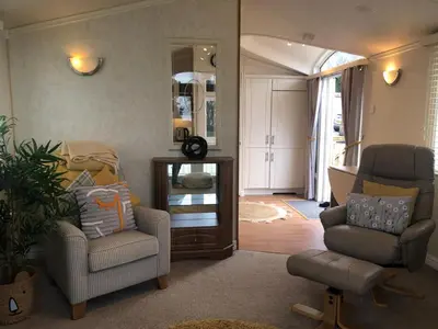 a living room with two chairs and a mirror at 29 The Beeches in Gilcrux