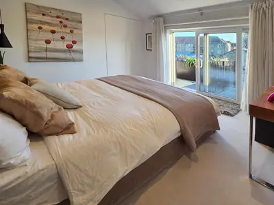 a bedroom with a large bed and a balcony at Central London stylish 2-Bed House, with 2 terraces in Moffat