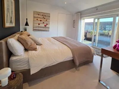 a bedroom with a large bed and a balcony at Central London stylish 2-Bed House, with 2 terraces in Moffat