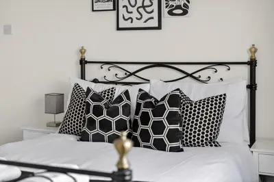 a bedroom with a black and white bed with pillows at Troon Golf by the Sea in Troon