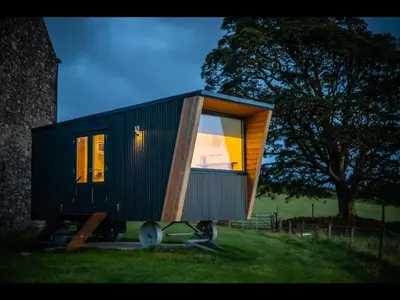 a small black tiny house sitting on the grass at Laverock How Shepherds Hut with private hot tub in Seascale