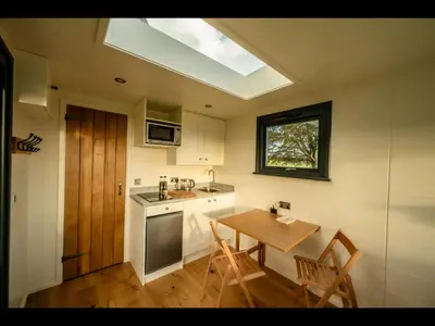 a kitchen with a wooden table and a skylight at Laverock How Shepherds Hut with private hot tub in Seascale