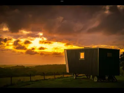a tiny house on a trailer in front of a sunset at Laverock How Shepherds Hut with private hot tub in Seascale