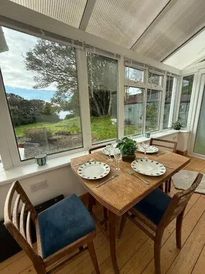 a dining room with a table and chairs and windows at Wee Knockinaam, Portpatrick - clifftop seaview in Portpatrick