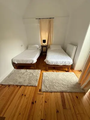 two beds in a room with wooden floors and rugs at Wee Knockinaam, Portpatrick - clifftop seaview in Portpatrick