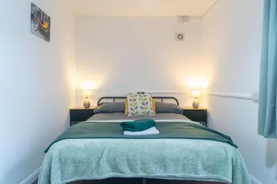 a bedroom with a bed with a green blanket and two lamps at Newton Flat in Carlisle