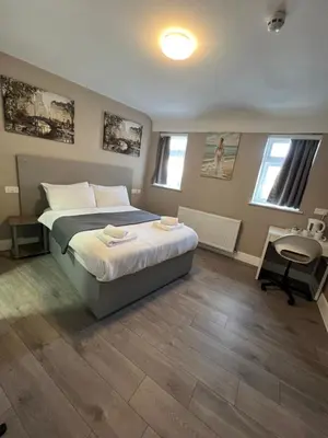 a bedroom with a bed and a desk and two windows at Rest Inn Edmonton in Moffat