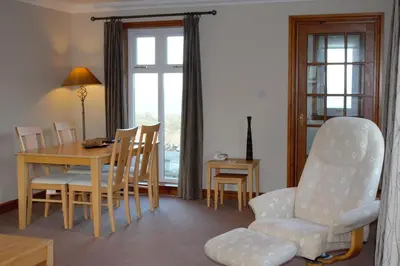 a living room with a table and a chair and a table and a dining room at Corsewall Lighthouse Hotel in Kirkcolm