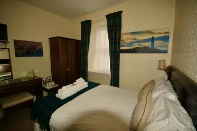 a bedroom with a bed and a desk and a window at Corsewall Lighthouse Hotel in Kirkcolm