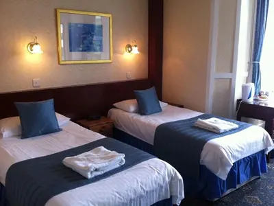 two beds in a hotel room with towels on them at Arrandale House in Douglas
