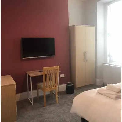 a bedroom with a bed and a desk with a television at Arrandale House in Douglas
