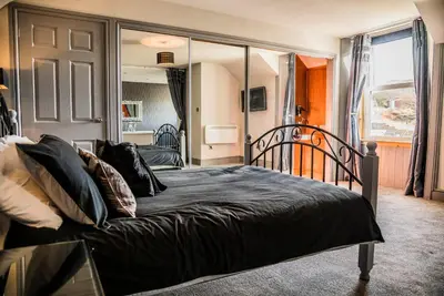 a bedroom with a bed with black sheets and a mirror at Mount Stewart Hotel in Portpatrick