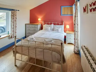 a bedroom with a bed and a red wall at Bankswood Cottage in Ruthwell