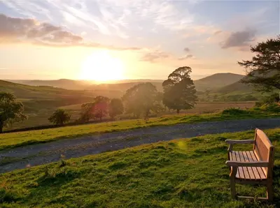 a bench in a field with the sunset in the background at The Dash Farmhouse in Bassenthwaite