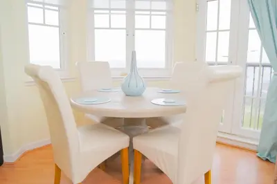a white dining room table with white chairs and a vase on it at Wood Court, Troon in Troon