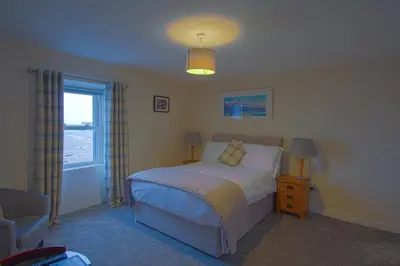 a bedroom with a bed and a chair and a window at The Harbour Inn in Garlieston