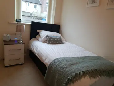 a bedroom with a bed with a pillow and a window at The Sawmills, Carlisle - Spacious 4 Bedroom Family House - Free WiFi - & Parking - Walk to Carlisle Castle in Carlisle