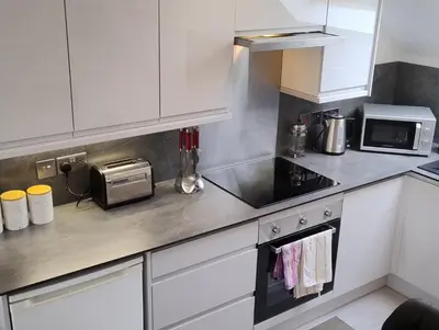 a kitchen with white cabinets and a sink and a microwave at The Sawmills, Carlisle - Spacious 4 Bedroom Family House - Free WiFi - & Parking - Walk to Carlisle Castle in Carlisle