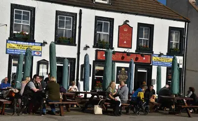 a group of people sitting at tables outside a building at Crown hotel in Portpatrick