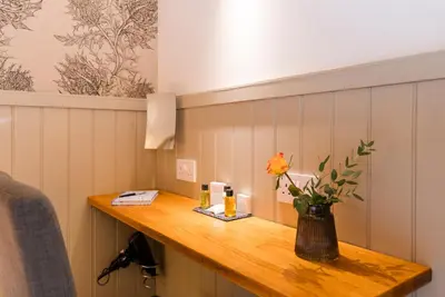 a room with a table with a vase of flowers on it at The Harbour Guest House in Irvine