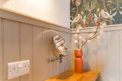 an orange vase sitting on a wooden table with a mirror at The Harbour Guest House in Irvine