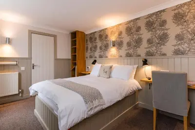 a bedroom with a bed and a desk and a chair at The Harbour Guest House in Irvine