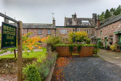 a sign in front of a house with a garden at Beech House in Greystoke