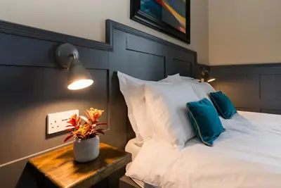 a bedroom with a bed with white sheets and blue pillows at Irvine Guest House in Irvine