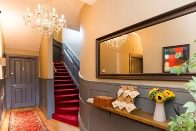 a hallway with a mirror and a red staircase at Irvine Guest House in Irvine