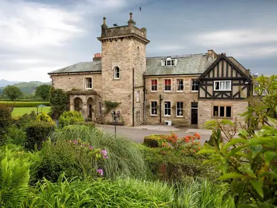 an old stone house with a tower in a garden at Hundith Hill Hotel in Cockermouth