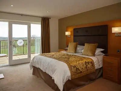 a bedroom with a large bed and a balcony at Hundith Hill Hotel in Cockermouth