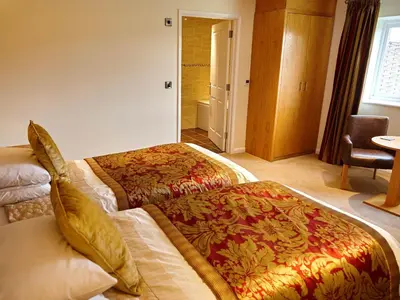 a hotel room with two beds and a chair at Hundith Hill Hotel in Cockermouth