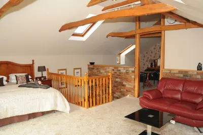 a bedroom with a bed and a red leather chair at Hundith Hill Hotel in Cockermouth