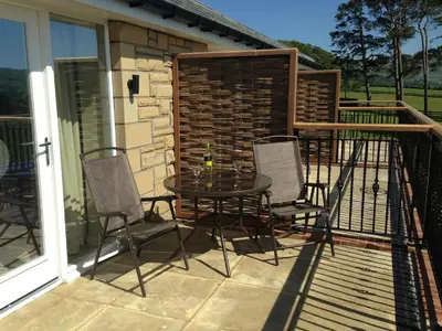 a patio with a table and chairs on a deck at Hundith Hill Hotel in Cockermouth