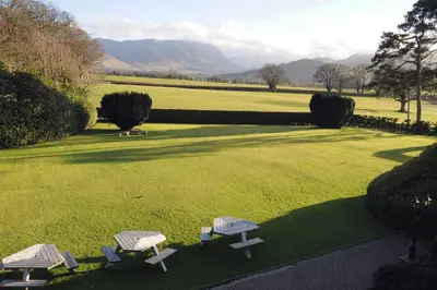 three picnic tables in a field with mountains in the background at Hundith Hill Hotel in Cockermouth