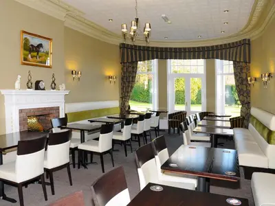a dining room with tables and chairs and a fireplace at Hundith Hill Hotel in Cockermouth